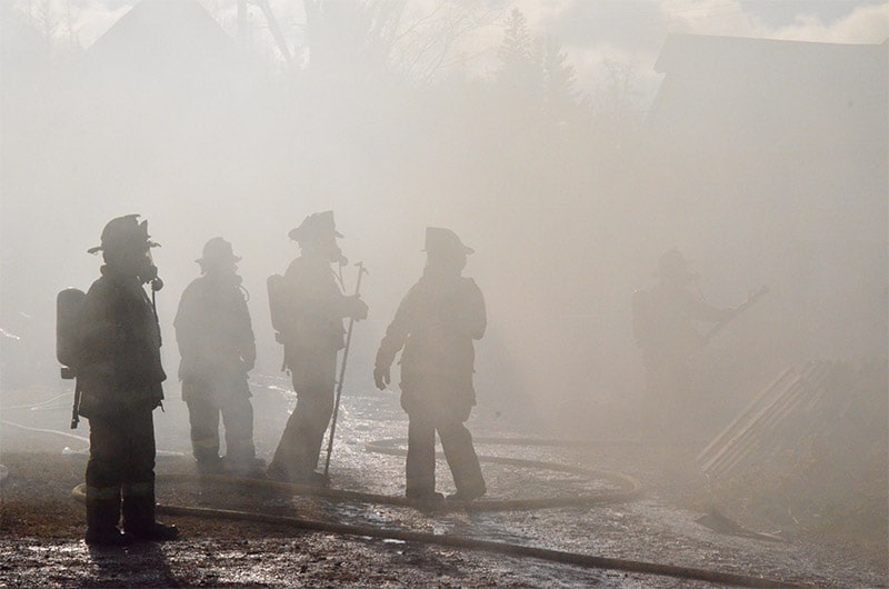 fire fighters walking through smoke putting fire out